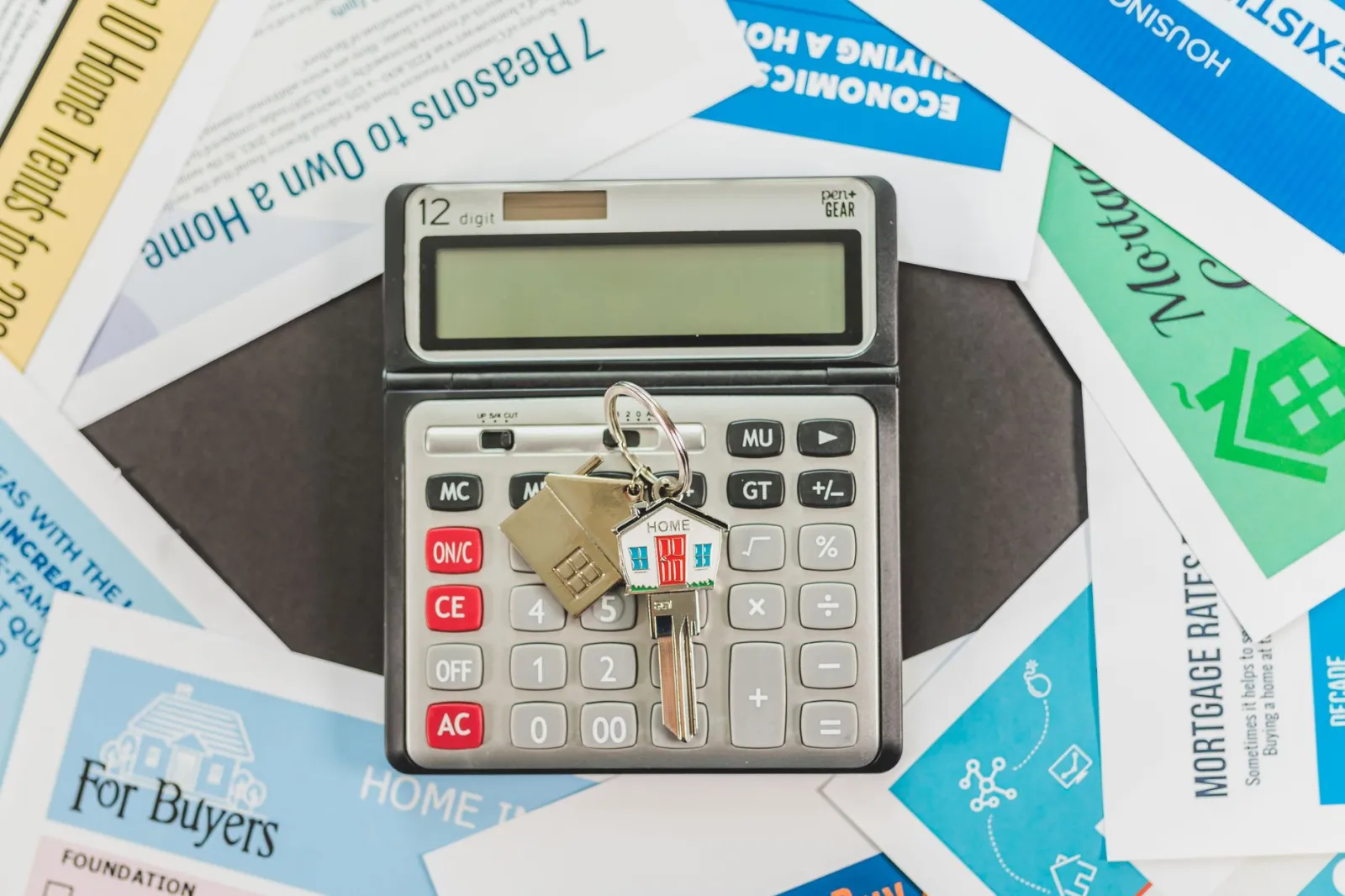 Calculator with keys and real estate documents symbolizes home buying finances.